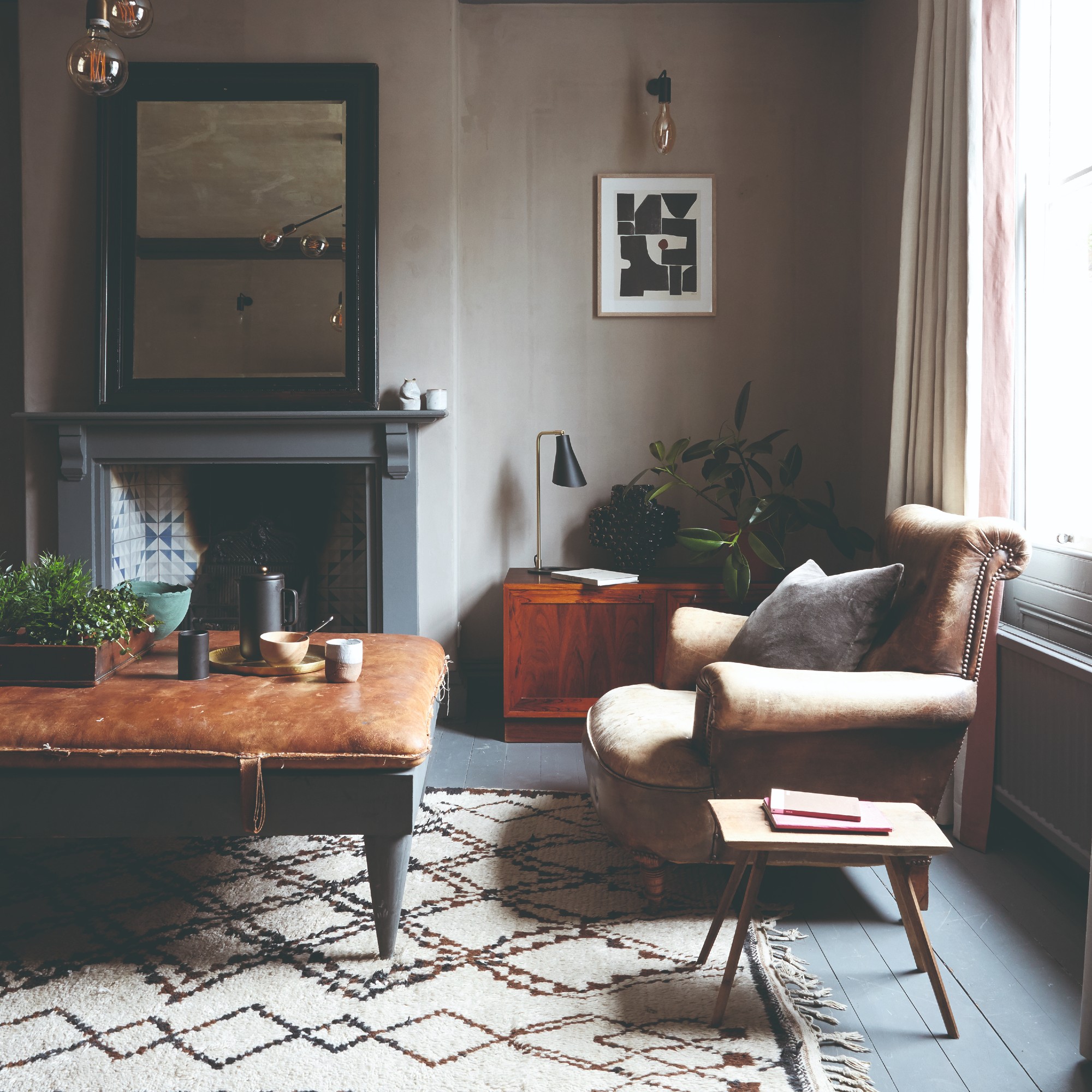 A living room with a large brown leather ottoman used as a coffee table placed on top of a Berber-style rug