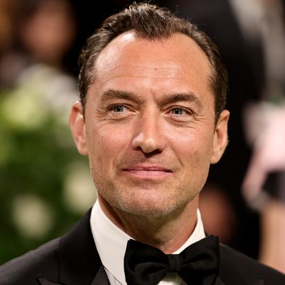 Jude Law wears a bow tie and smiles on the red carpet