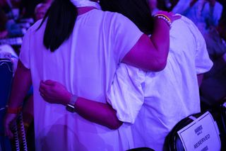 Attendees wearing white embrace at the United Center on August 22, 2024, on the fourth day of the Democratic National Convention in Chicago, Illinois.