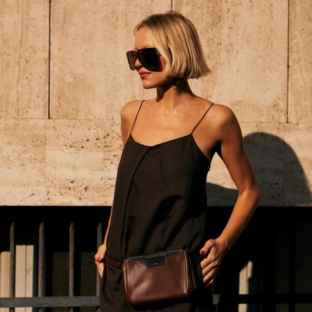 woman with short blonde hair wearing sunglasses black tank top and brown fanny pack