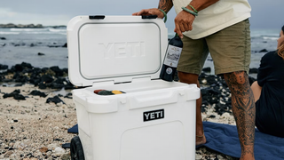 Man taking wine bottle out of Yeti cooler on beach