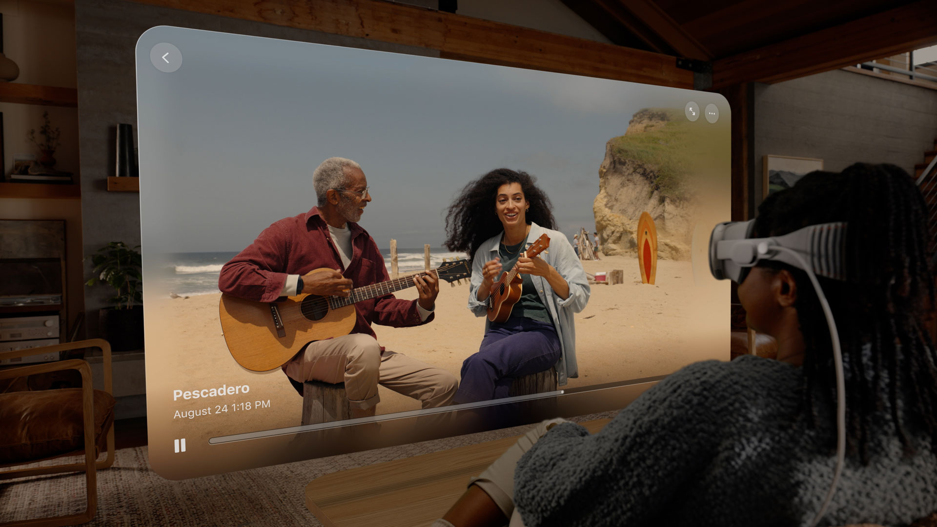 A person wearing a headset on a couch watches an Apple Vision Pro spatial video shot on the beach.