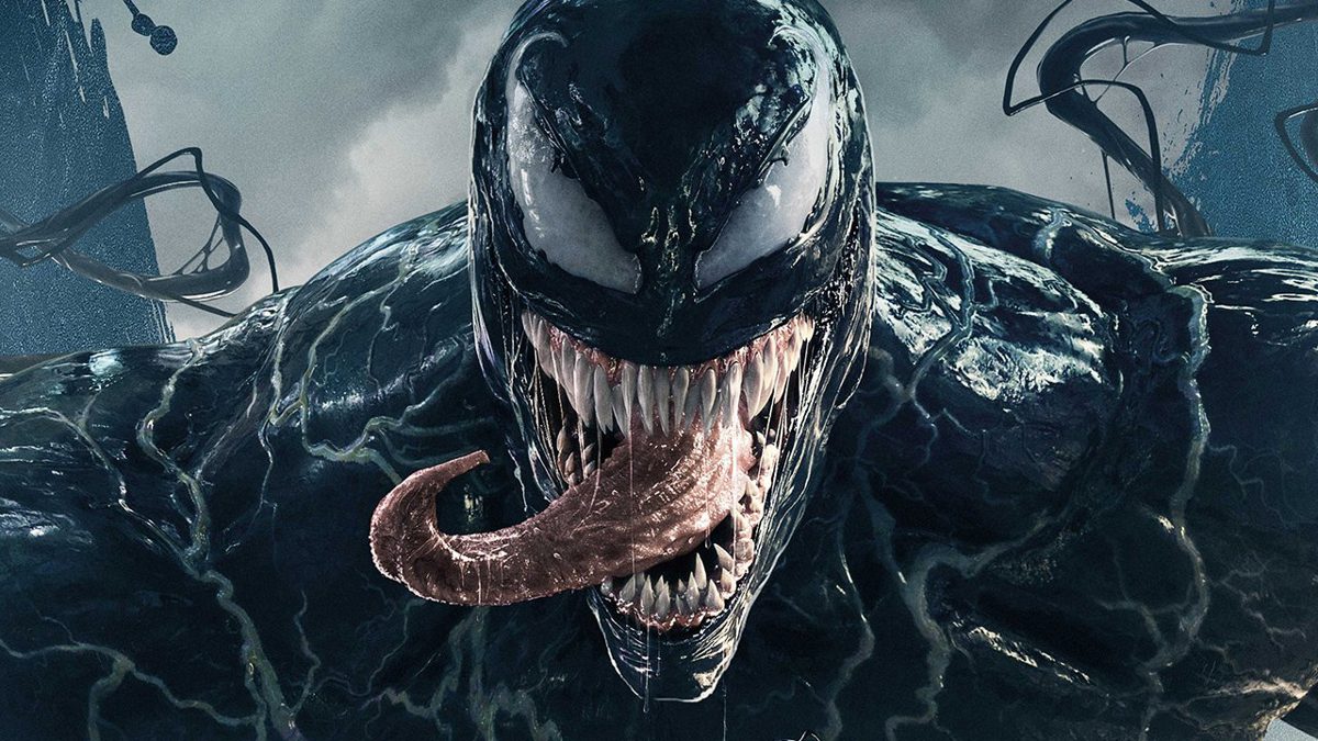 A screenshot of Venom with his tongue sticking out as he looks straight at the camera