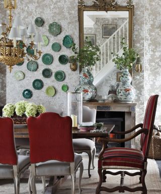 dining room with red chairs, fireplace, mirror and green plates on wall