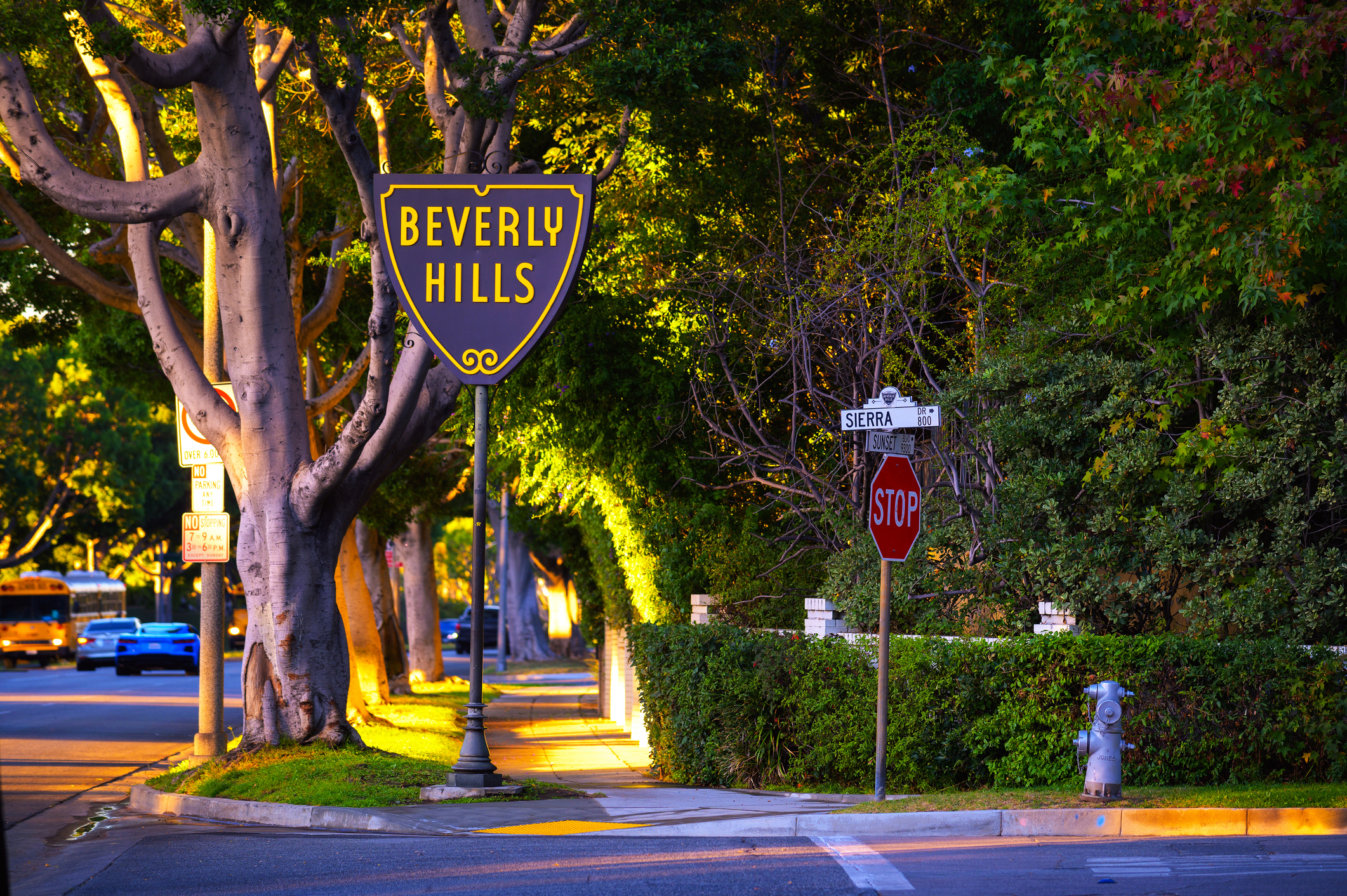 Beverly Hills, California, USA - November 3, 2023 : Beverly Hills sign at the corner of Sierra Drive and Sunset Boulevard, surrounded by lush greenery and illuminated by warm sunlight