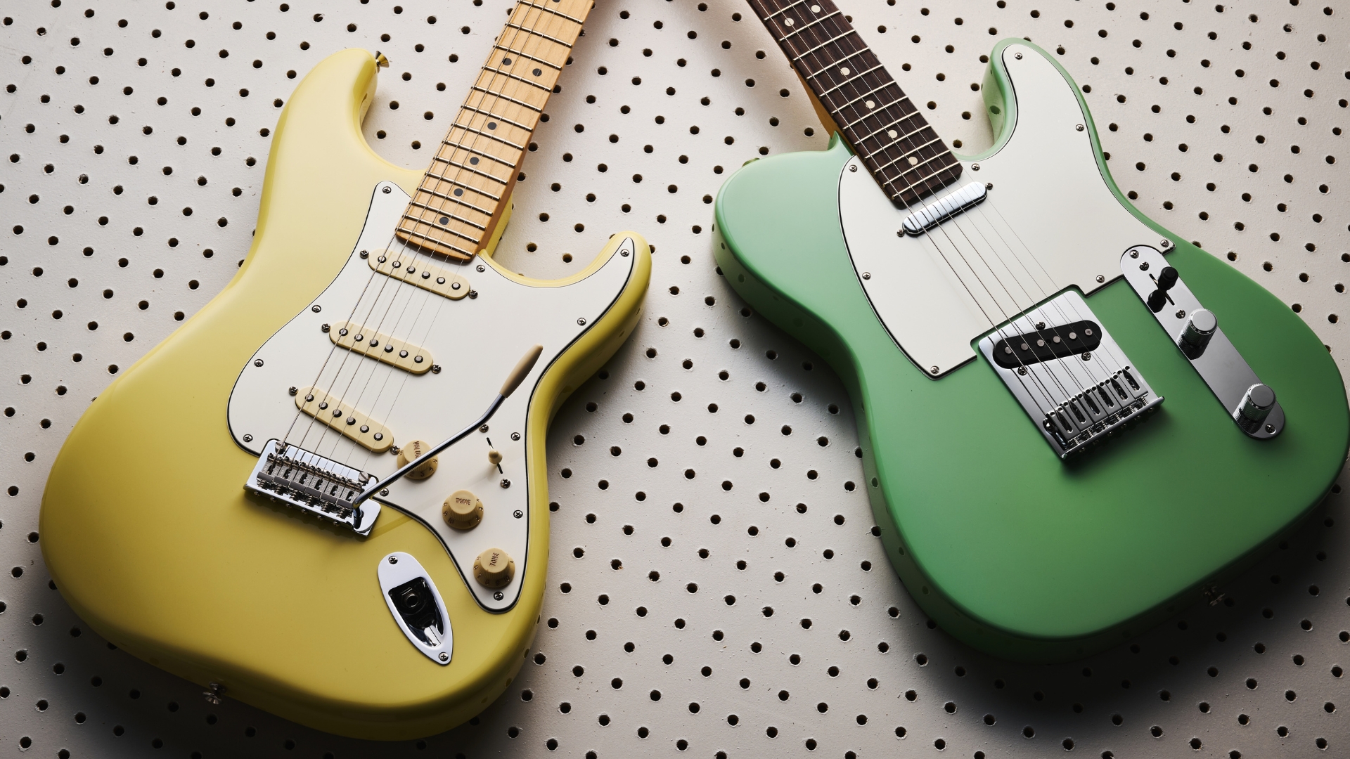 A Fender Player II Stratocaster and Telecaster on a white piece of wood with lots of holes in it