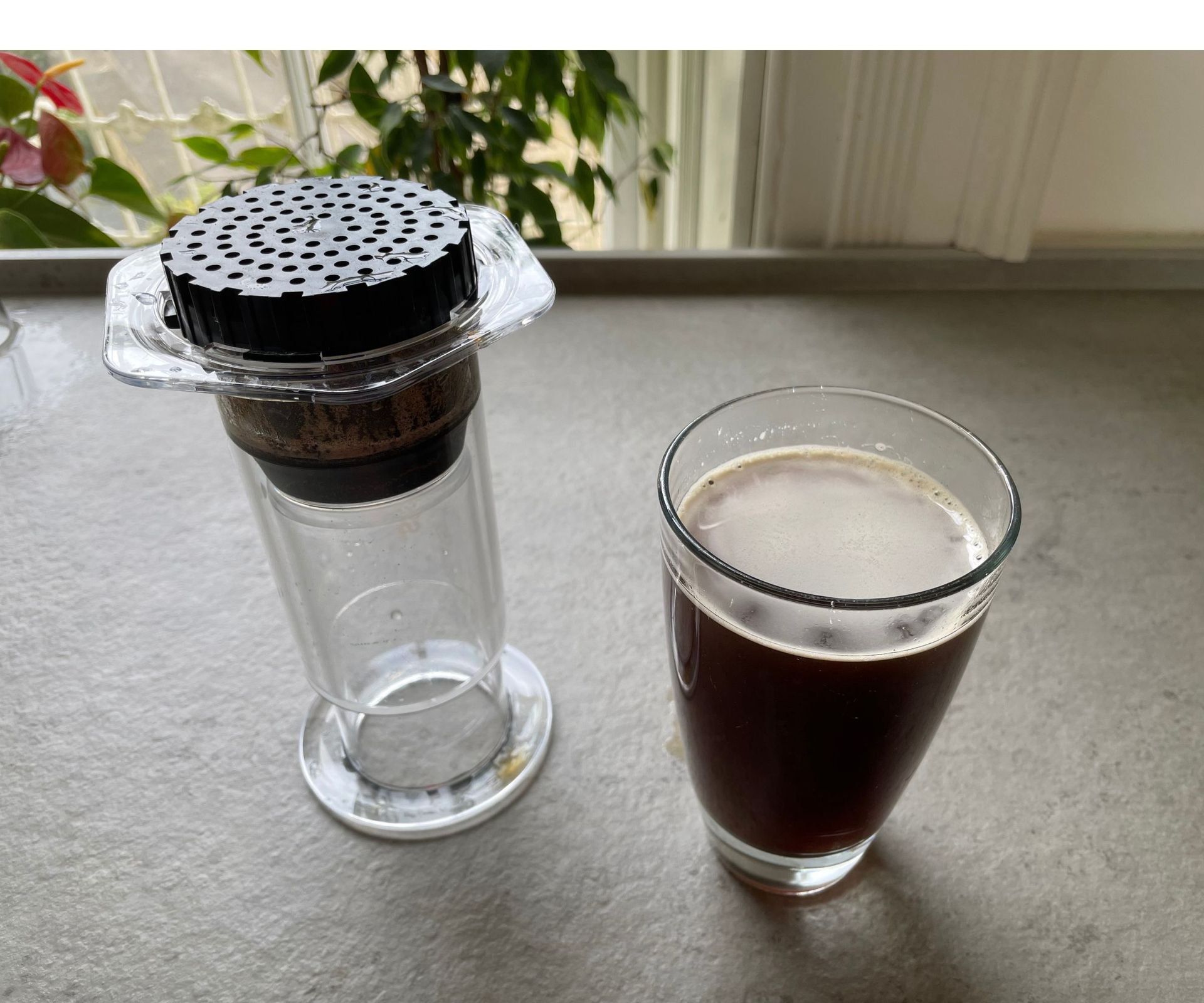 AeroPress coffee maker next to an Americano