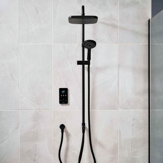 Black showerhead and shower hose wall mounted on marble effect tiles