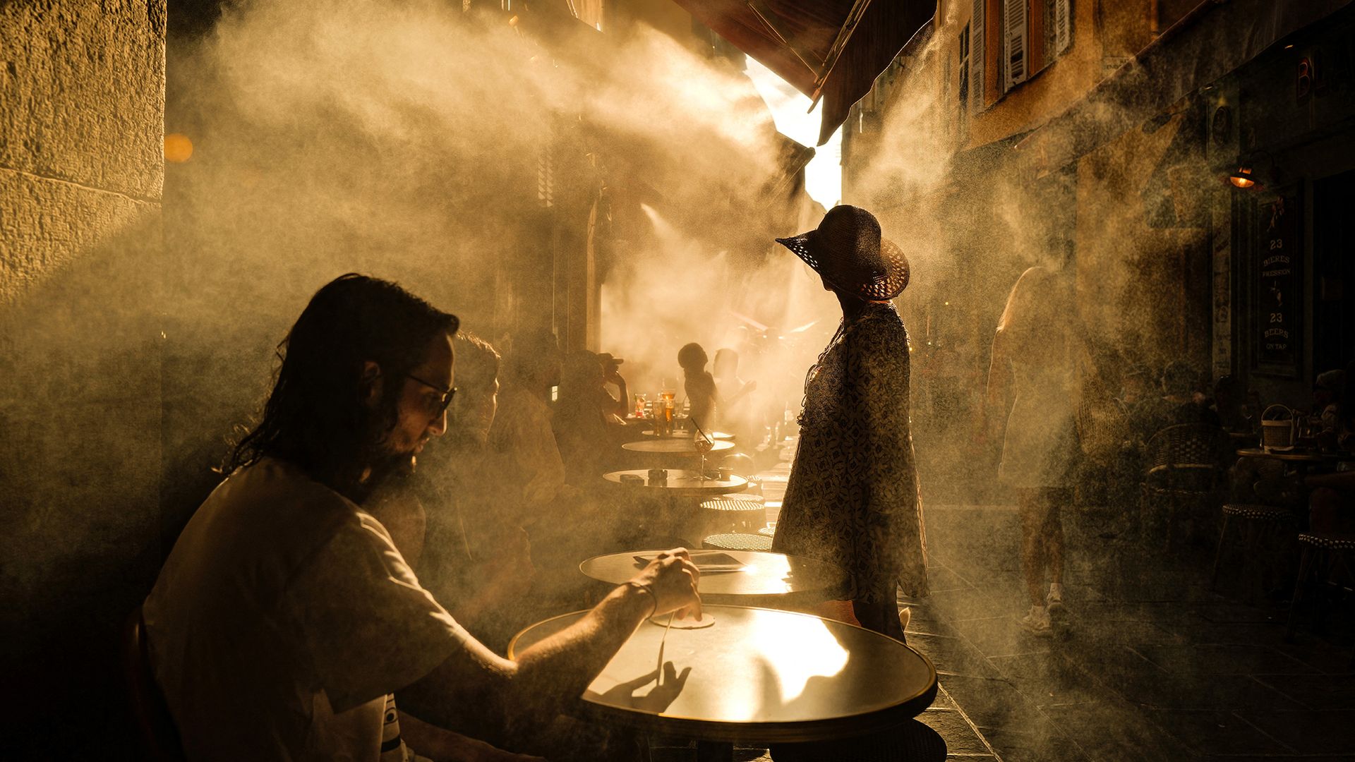 
                                Patrons cool off beneath misting sprinklers at a cafe in Nice, France
                            