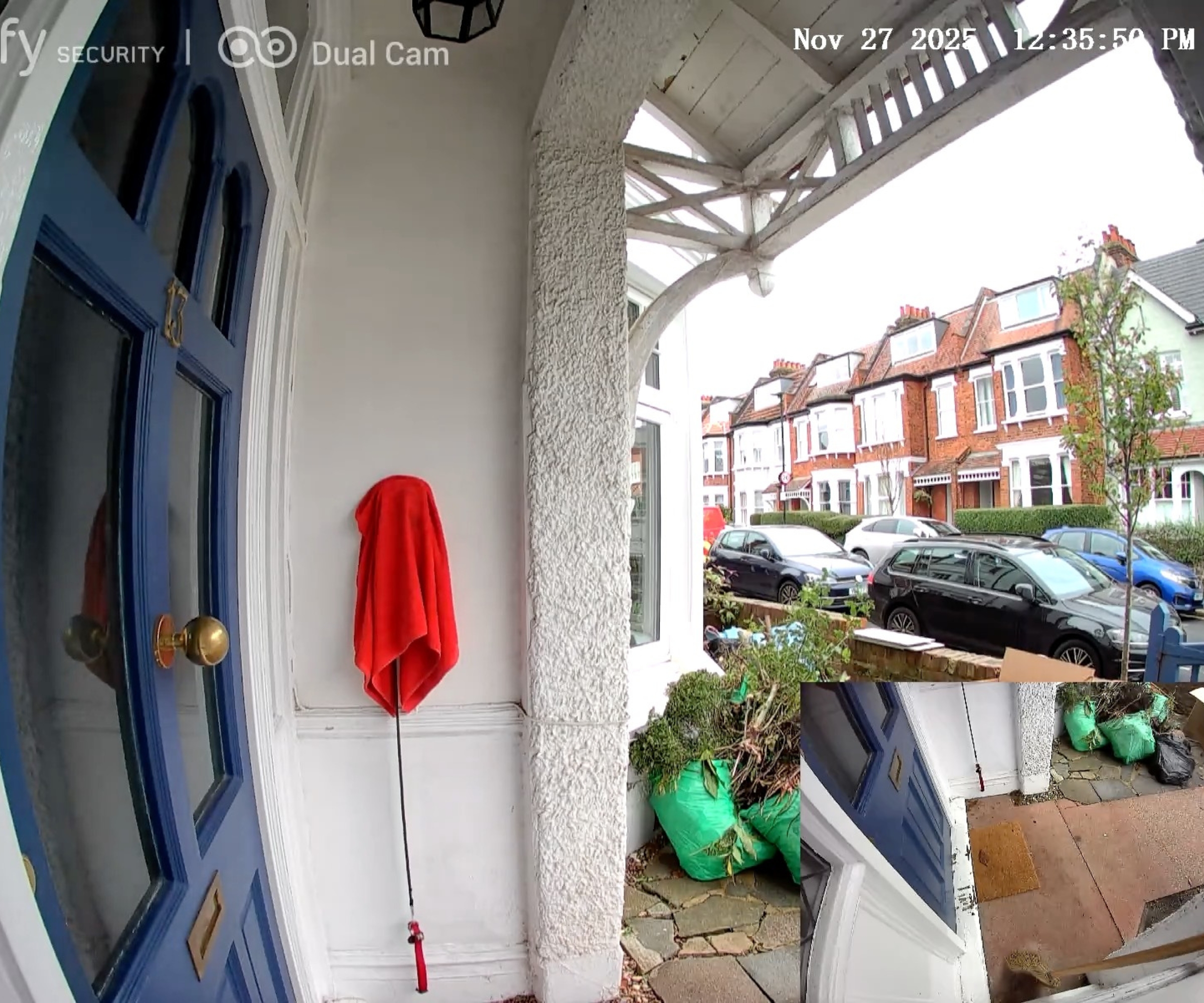 Screenshot of footage on eufy app from eufy S330 video doorbell, showing porch with blue front door, a hanging red towel, and a street with cars and houses. In the bottom right corner is a smaller screenshot of the porch floor.