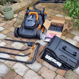 Worx WG743E lawn mower in parts on paving