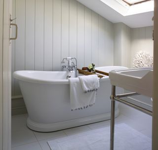 boat bath under eaves in bathroom with wood panel walls