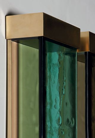Upclose image of a wall light featuring gold and green detail