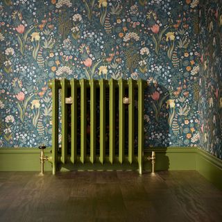 green radiator with painted skirting board and floral decorative wallpaper