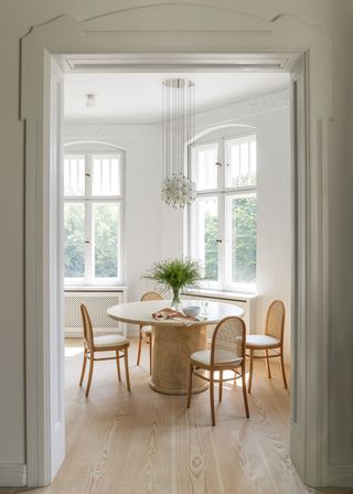 Small white dining room with marble dining table and cane chairs