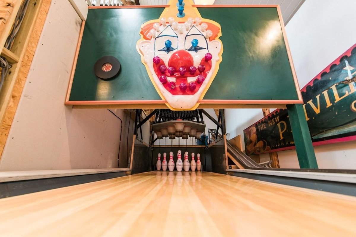 A bowling alley with a clown face above the pins