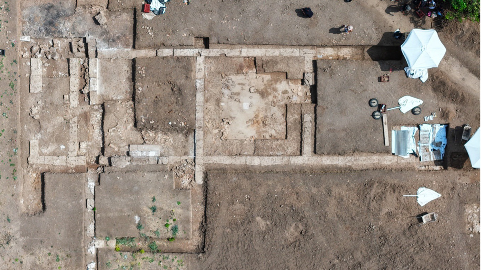 An aerial view of an archaeological site showing square areas that have been excavated.