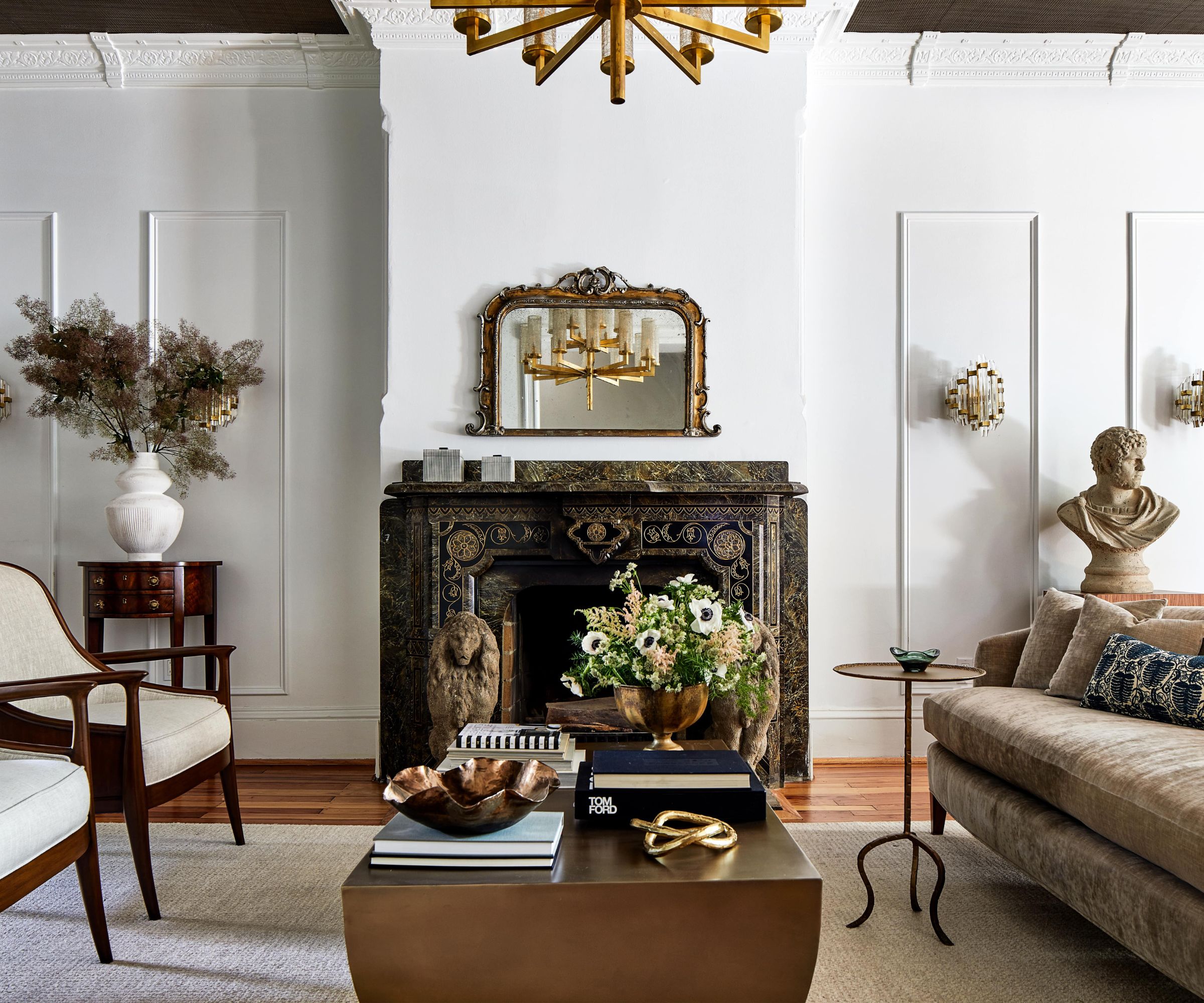 Living room with marble fireplace, crown molding, gilded mirror, coffee table, velvet sofa and Grecian bust