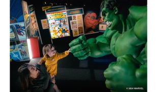 A child fist bumps The Hulk at the Marvel exhibit. 