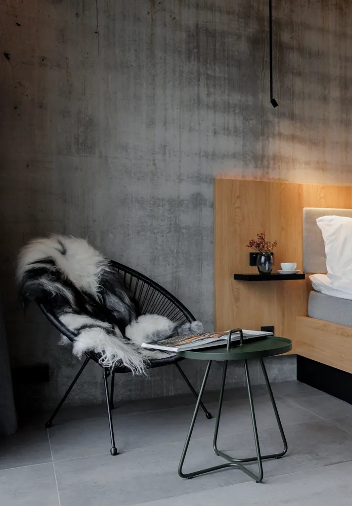 An Icelandic hotel immersed in raw natural landscapes with wild horses boasts brutalist interiors mixing exposed cement, iron, and glass surfaces with western-style design accents.