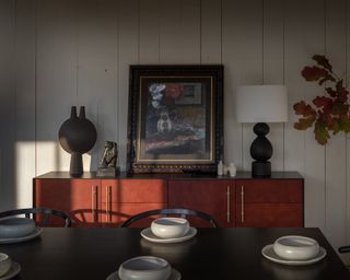 A dining room with a red ochre and black sideboard