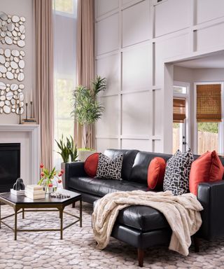 A living room with a black leather sofa, millwork on the walls and a textured rug