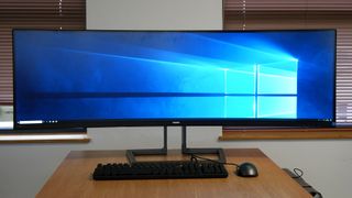 Philips Brilliance 499P9H monitor on a table between two windows and displaying the Windows 10 desktop