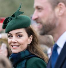 Princess Kate wearing a green hat and smiling at Prince William
