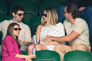 Margot Robbie sits with her husband at Wimbledon wearing a backless polka dot cape dress