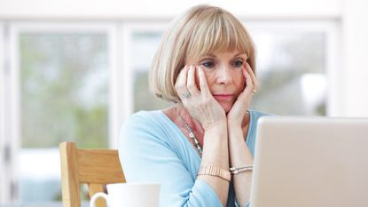 A female retiree sits at a computer.