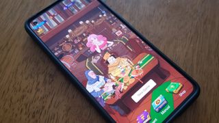A phone sits on a table with the tavern from Dicey Elementalist showing on the screen. 
