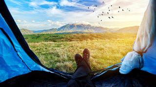 man legs inside tent, lying down and relaxing in his mountain adventure