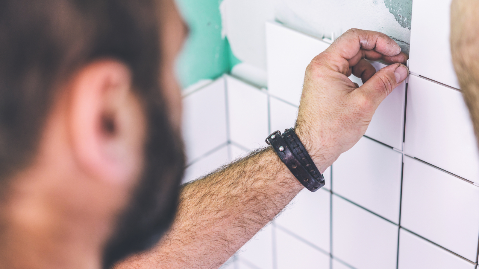 A person positioning tile spacers between square tiles