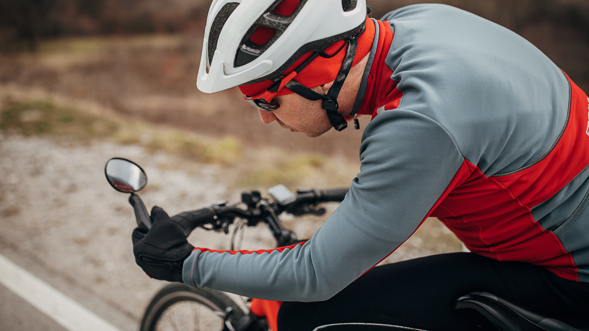 A cyclist adjusting a mirror on his bicycle