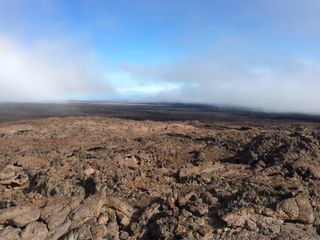 The HI-SEAS habitat is located on Mauna Loa, on the island of Hawaii. This image shows a view looking down the mountain from the dome. The ground is made up of jagged lava rock.