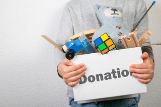 Organizing a playroom with toys in a donation box held by a child