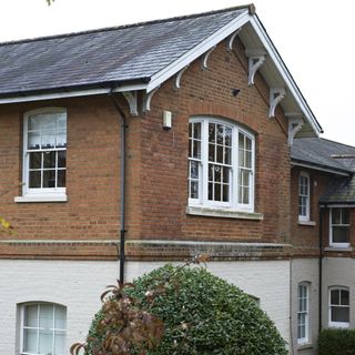 house exterior with bricked wall and white windows and slate tiles roof