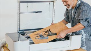 The best Glowforge machines; a photo of a man pulling engraved wood from a laser printer