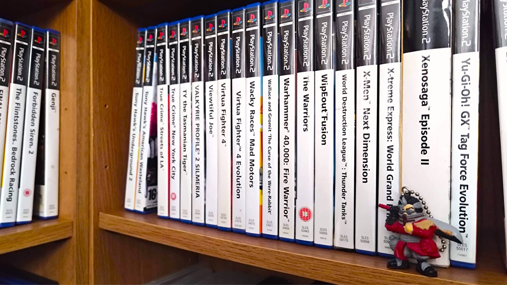 PS2 games on shelf with Auron Final Fantasy X keychain on right.