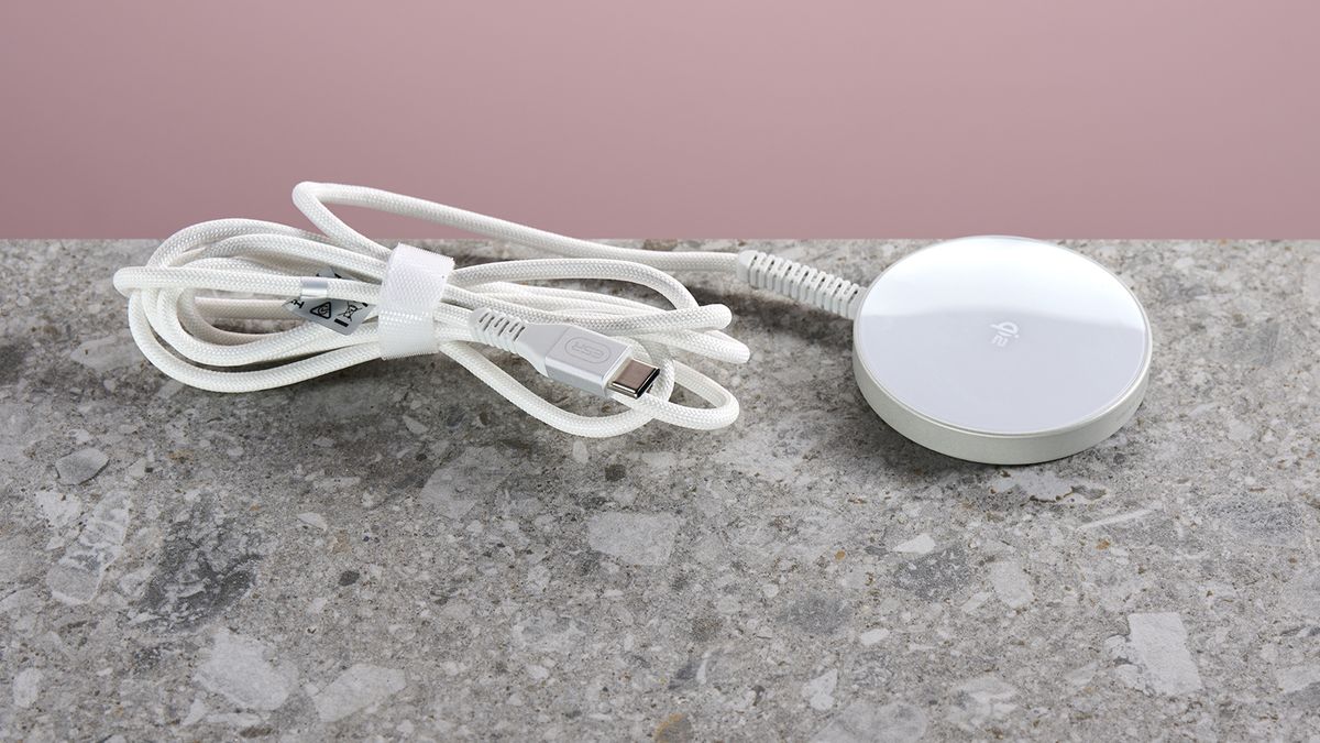 The ESR Qi2 Mini Wireless Charger sits on a light grey stone-effect surface against a pink background. The folded and secured charging cable extends from the left of the charging pad.