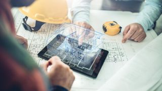 2 men looking at architectural plans with 3d model of house generated from an ipad