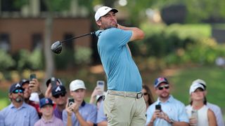 Scottie Scheffler, wearing green, plays a shot during a golf tournament