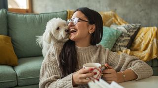 Woman drinking tea with Velcro dog looking over her shoulder