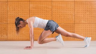 Woman performs plank with knee tuck