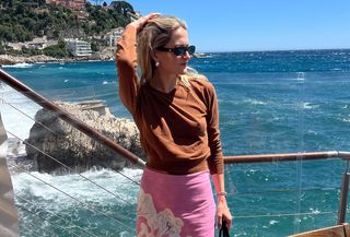 Eliza Huber in Nice, France wearing a Zara brown V-neck sweater with a pink printed Zara skirt.