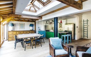 An open plan kitchen with wooden beams, leather chairs, and wooden furniture