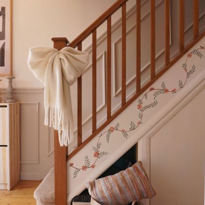 Staircase with floral mural painted up the sideboard and fabric white bow tied around banister pole