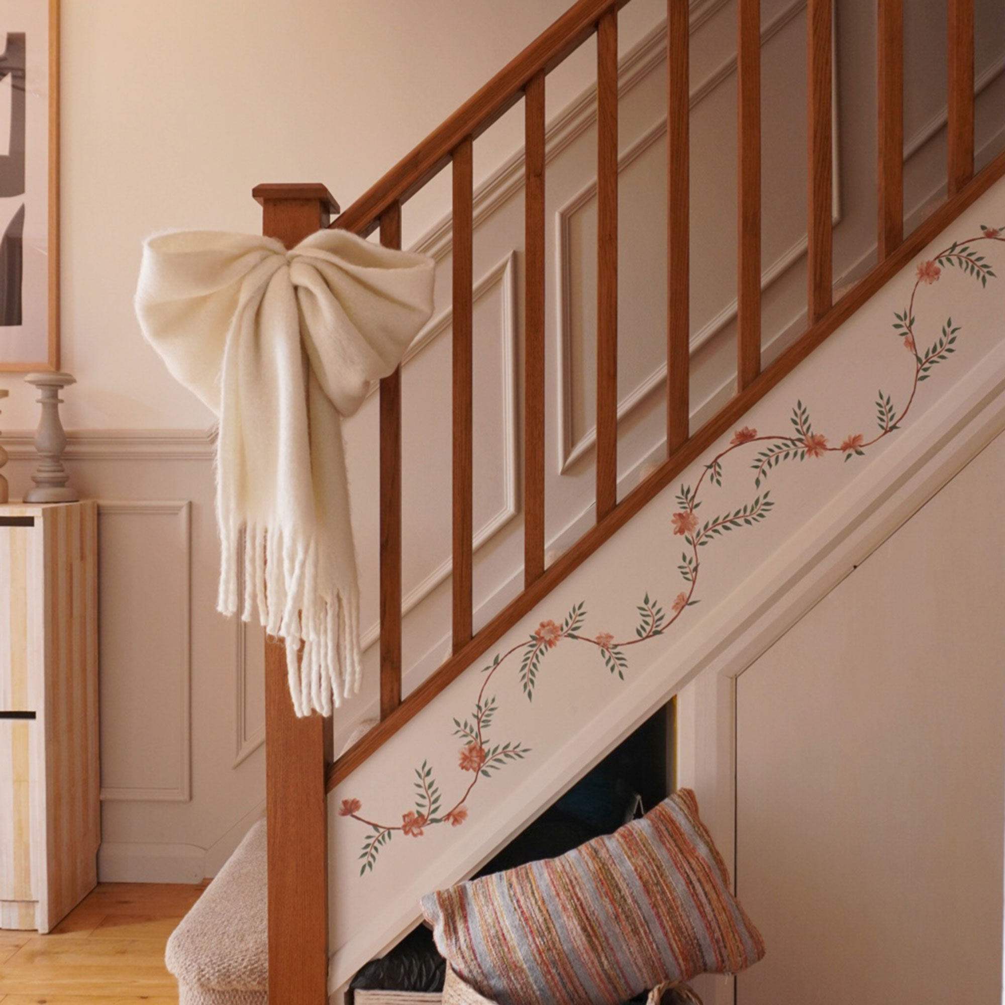 Staircase with floral mural painted up the sideboard and fabric white bow tied around banister pole