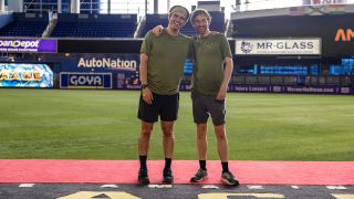 Carson and Jack make it to Phil and the mat first to win The Amazing Race Season 37, then pose for a picture facing the camera.