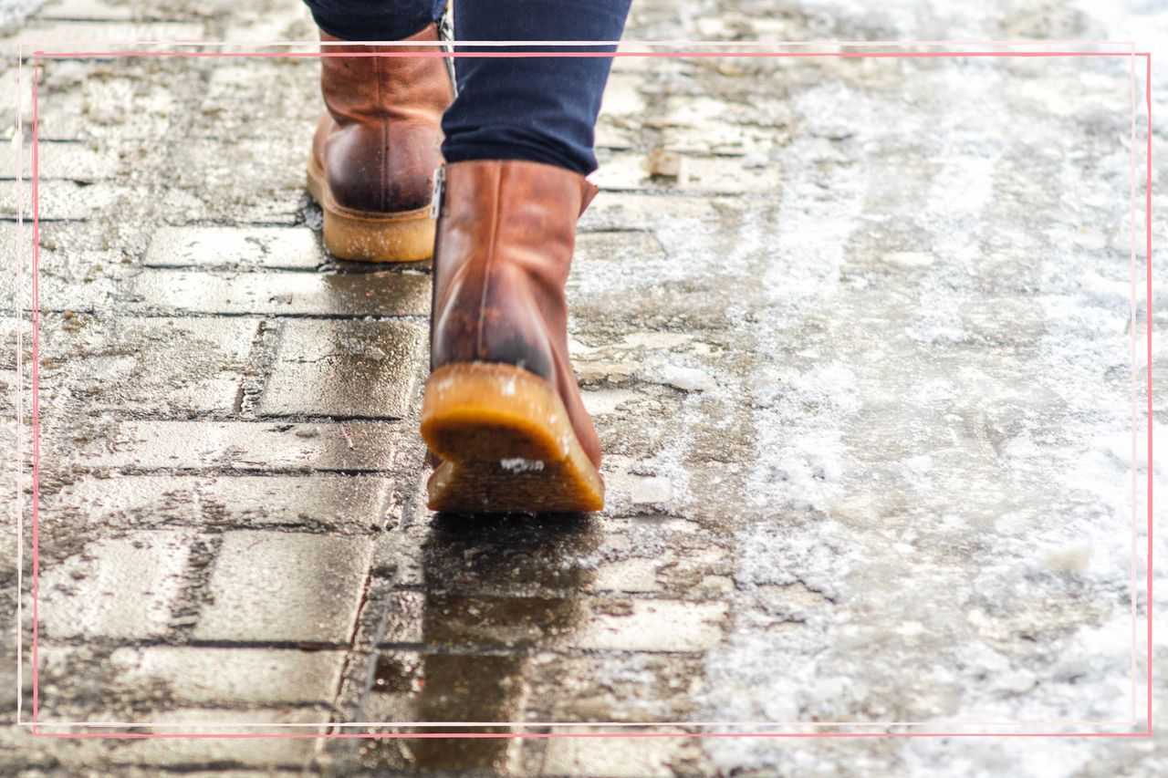 A close up of a person walking on wet and icy pavement